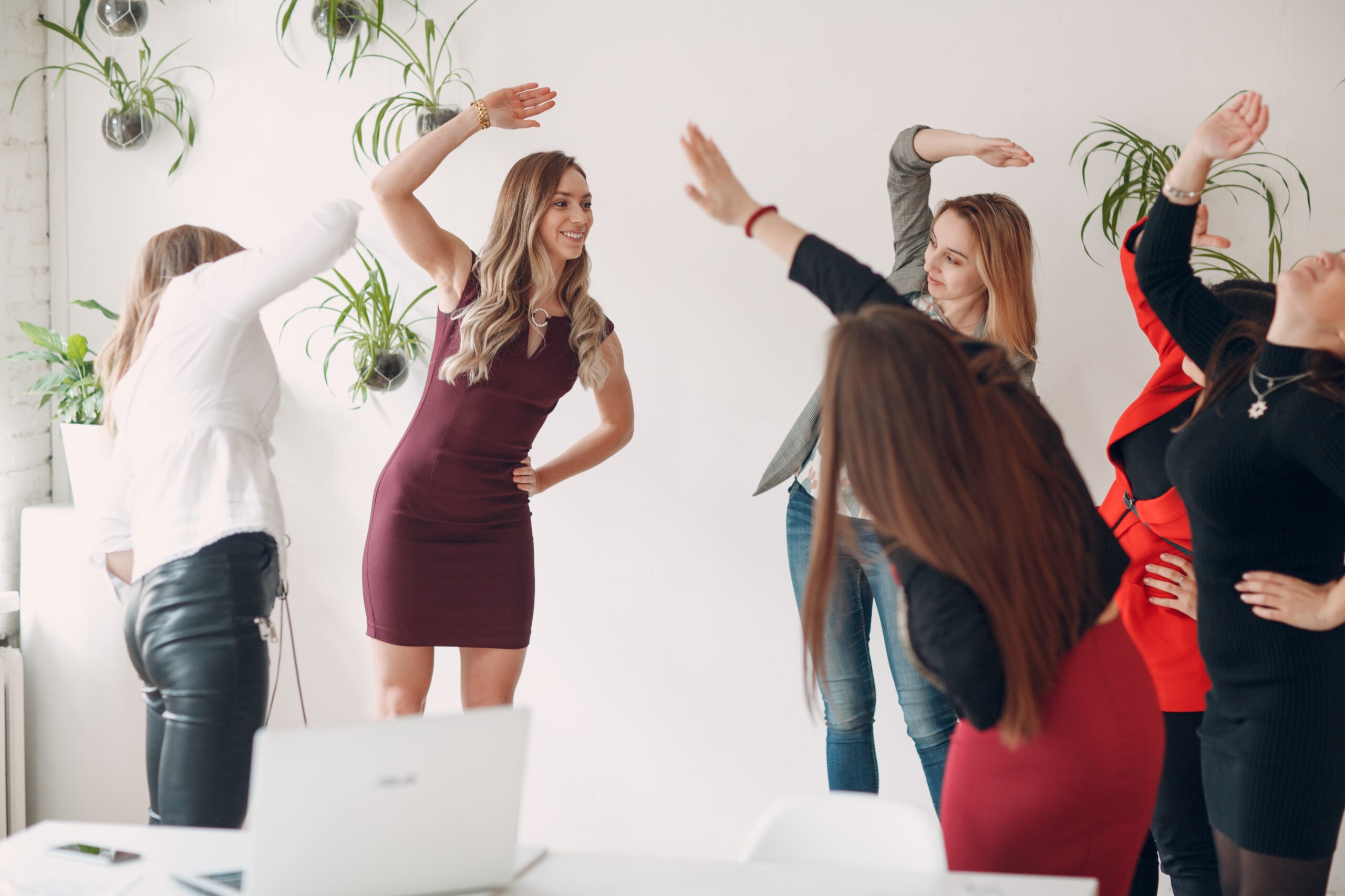 Team women doing exercises in office. Exercising females at work. Benefits of fitness and gymnastics for employees and managers.